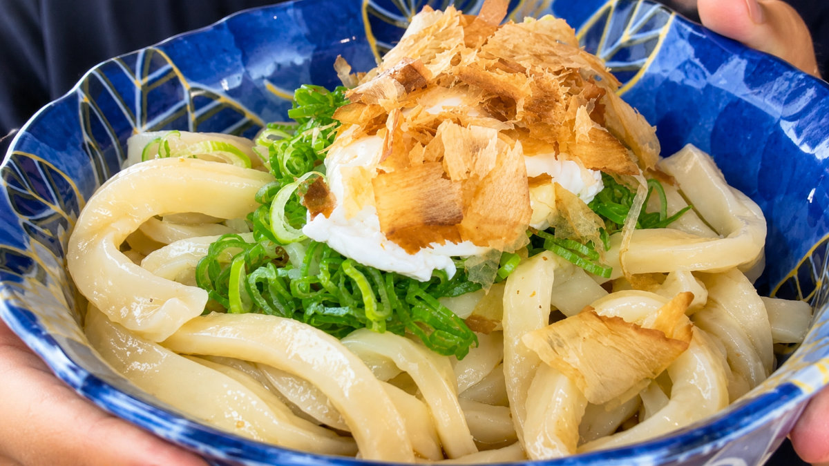 Ciotola di udon caldi in brodo, con guarnizioni tradizionali.